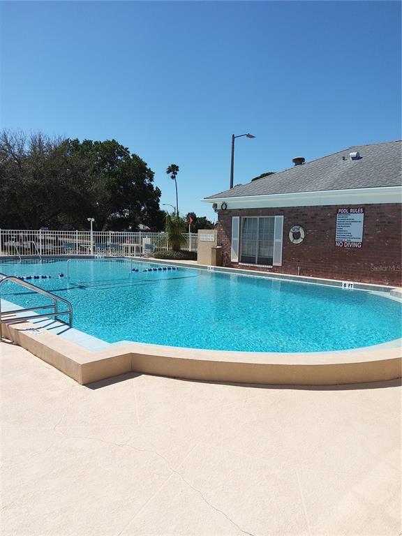 A swimming pool with a metal railing sits in front of a brick building — 3440 41ST AVE SOUTH UNIT 187, ST PETERSBURG, FL