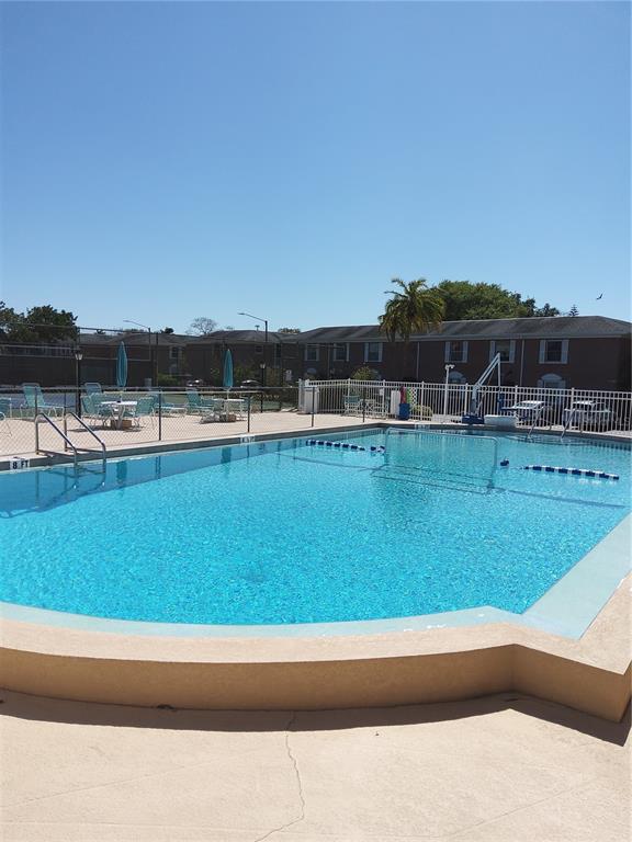 An outdoor swimming pool with a surrounding patio and apartment buildings in the background — 3440 41ST AVE SOUTH UNIT 187, ST PETERSBURG, FL