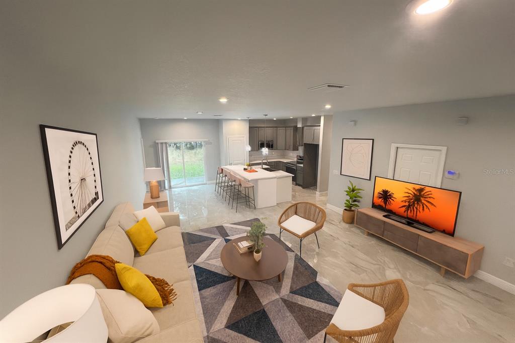 An open-concept living room and kitchen featuring tile flooring, a large island, and modern decor — 373 AMBERJACK, POINCIANA, FL