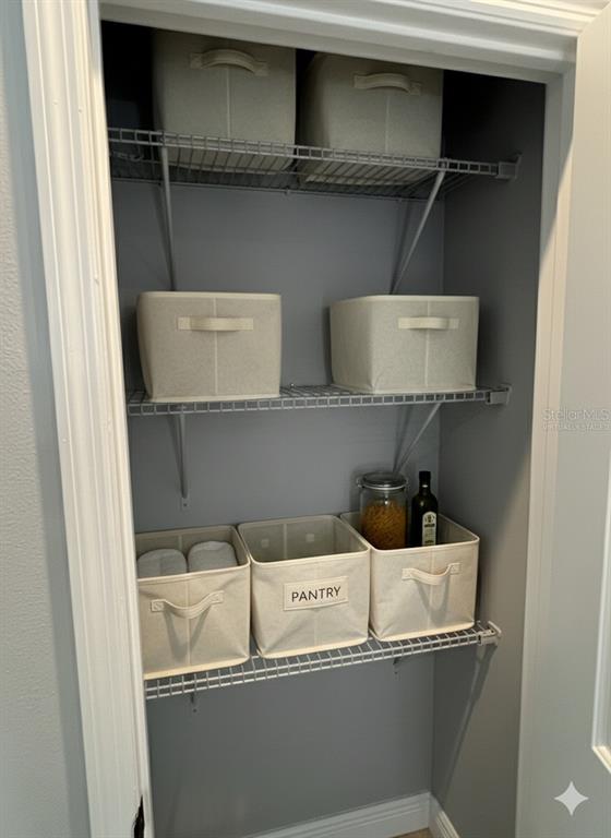 A pantry closet features wire shelving holding several beige fabric storage bins — 373 AMBERJACK, POINCIANA, FL