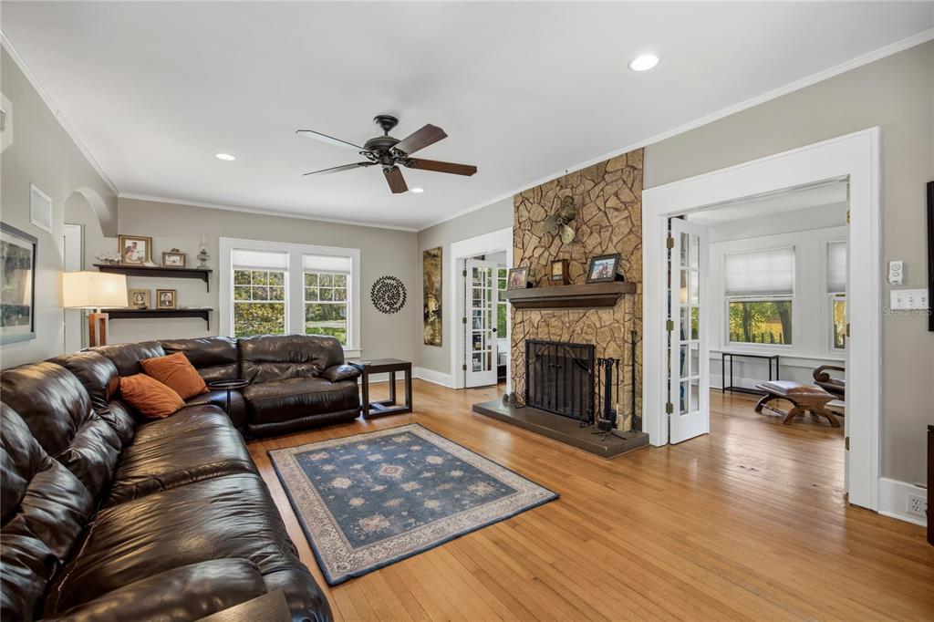 A living room with a stone fireplace, hardwood floors, and a large brown leather sectional — 720 NE BOULEVARD, GAINESVILLE, FL