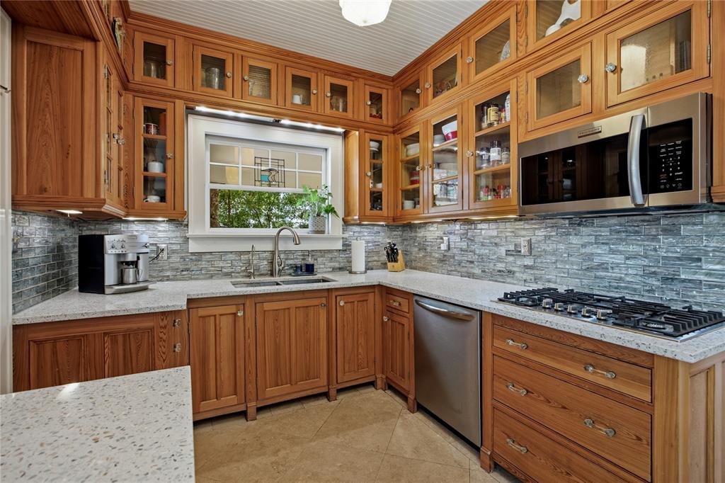 A kitchen features wood cabinets, a stainless steel microwave, a gas cooktop, and tile backsplash — 720 NE BOULEVARD, GAINESVILLE, FL