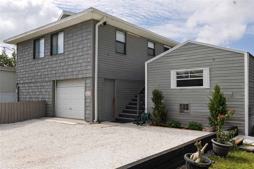 A two-story gray house with a garage, exterior stairs, and a gravel driveway — 29103 ORVA DRIVE, PUNTA GORDA, FL