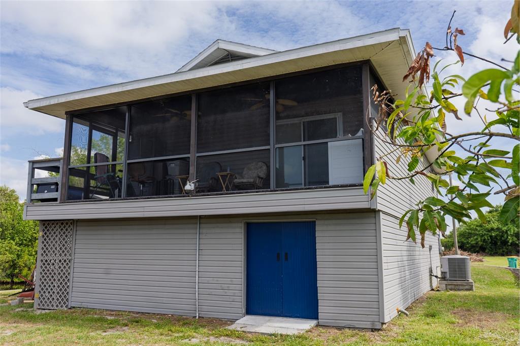 A two-story house with a screened-in upper porch and blue double doors on the ground — 29103 ORVA DRIVE, PUNTA GORDA, FL