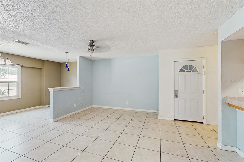An interior view shows a tiled living area with a light blue accent wall and door — 117 N MERCURY AVENUE UNIT 117, CLEARWATER, FL