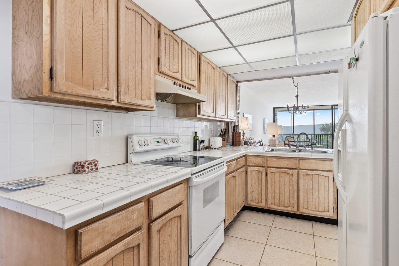 A kitchen with light wood cabinets, white tile countertops, and a white electric range — 13 Royal Palm Way # 602, Boca Raton FL 33432, BOCA RATON, FL