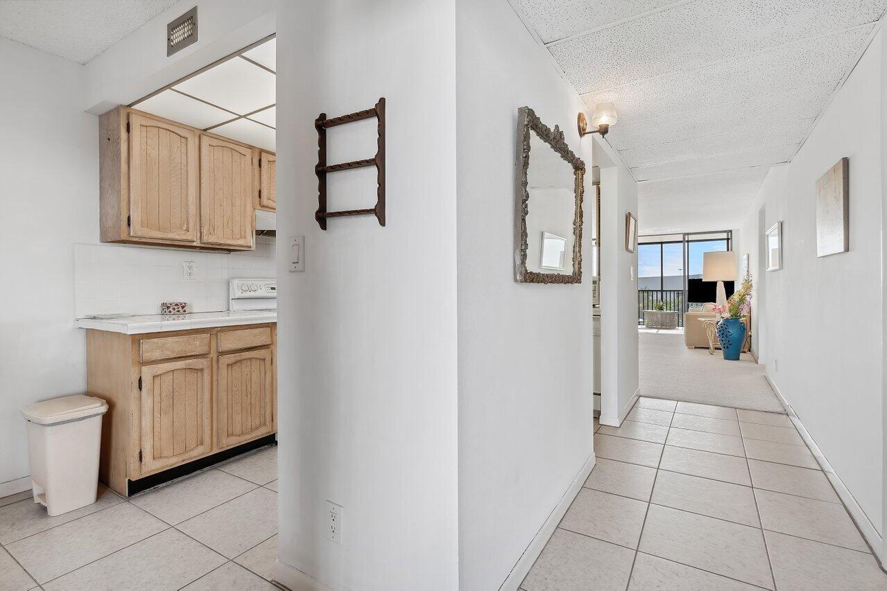 A view from a tiled hallway looking into a kitchen and a carpeted living area — 13 Royal Palm Way # 602, Boca Raton FL 33432, BOCA RATON, FL