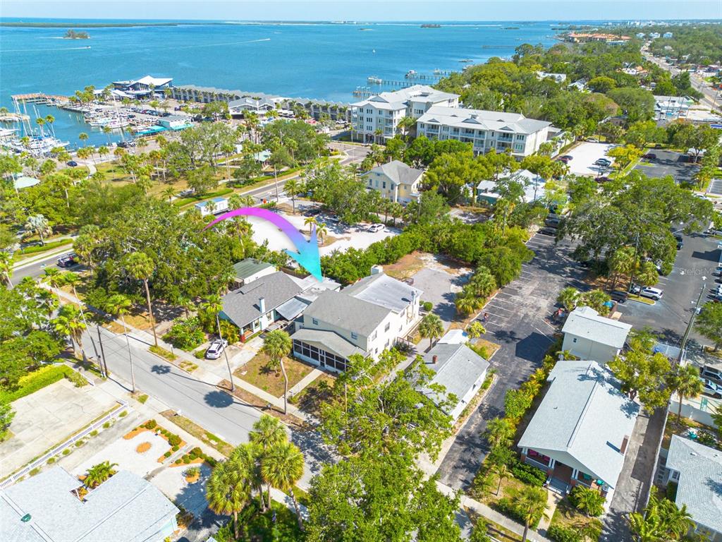 An aerial view shows a multi-story house with a screened porch near a marina — 220 SCOTLAND STREET, DUNEDIN, FL