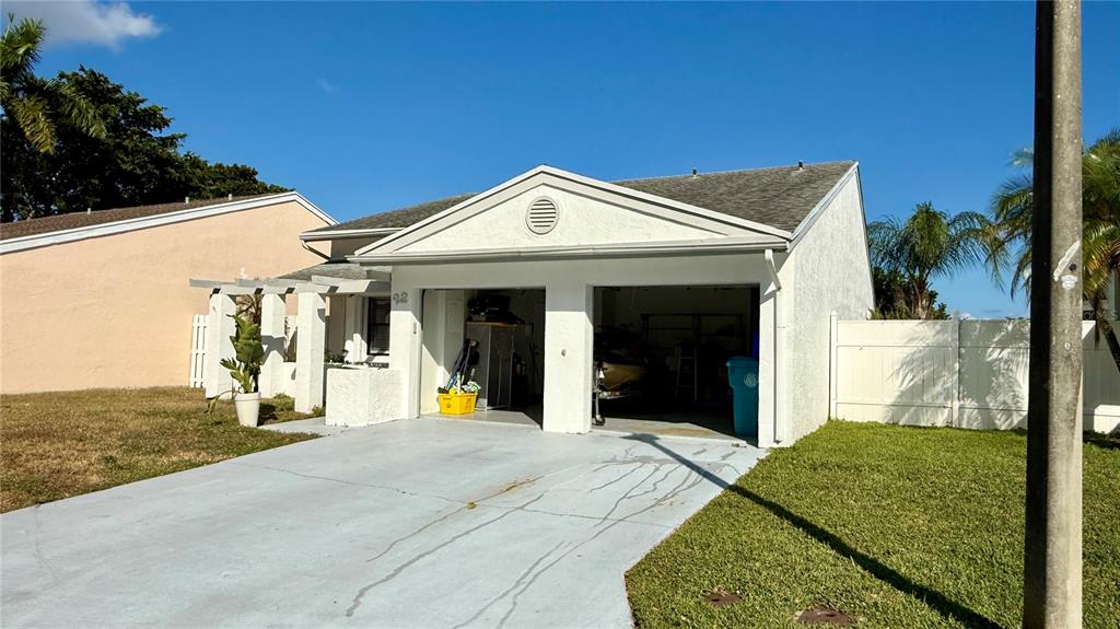 A white house with a two-car garage and a concrete driveway under a blue sky — 22 PAXFORD LANE, BOYNTON BEACH, FL
