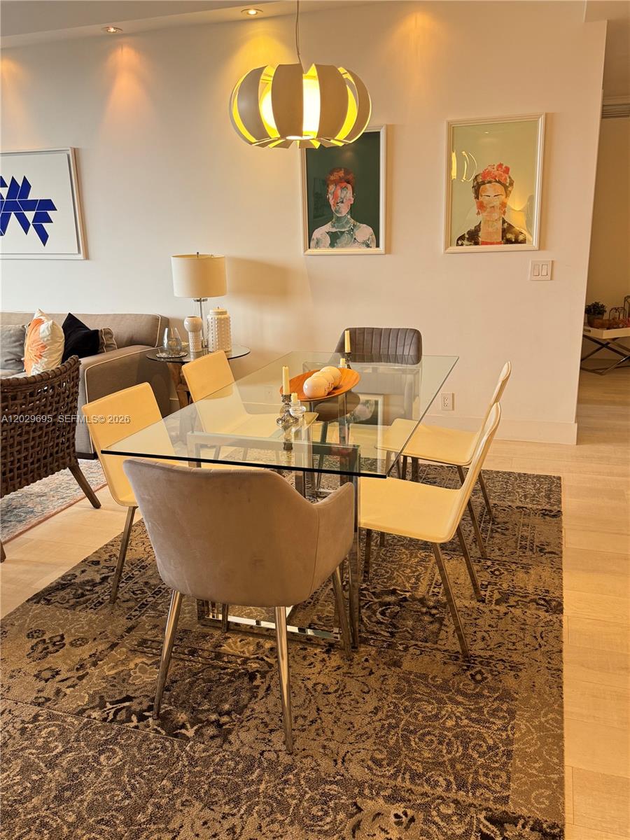 A dining area features a glass table, modern chairs, a pendant light, and framed artwork — 151 Crandon Blvd # 405, Key Biscayne FL 33149, KEY BISCAYNE, FL