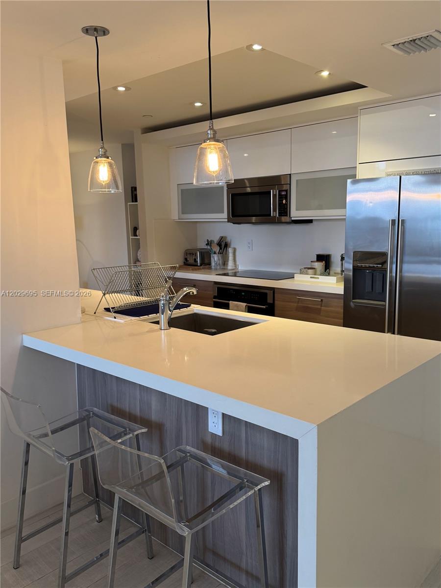 A modern kitchen features a white quartz island, stainless steel appliances, and two clear barstools — 151 Crandon Blvd # 405, Key Biscayne FL 33149, KEY BISCAYNE, FL