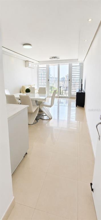 A bright dining area features white tile floors, a modern table with chairs, and balcony access — 1607 AVENIDA JUAN PONCE DE LEON UNIT 1611, SANTURCE, PR