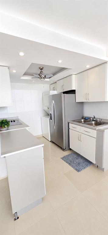 A kitchen features white cabinets, stainless steel appliances, a ceiling fan, and light tile flooring — 1607 AVENIDA JUAN PONCE DE LEON UNIT 1611, SANTURCE, PR