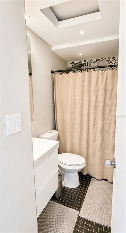 A small bathroom features a white vanity, a toilet, and a shower with a beige curtain — 1607 AVENIDA JUAN PONCE DE LEON UNIT 1611, SANTURCE, PR