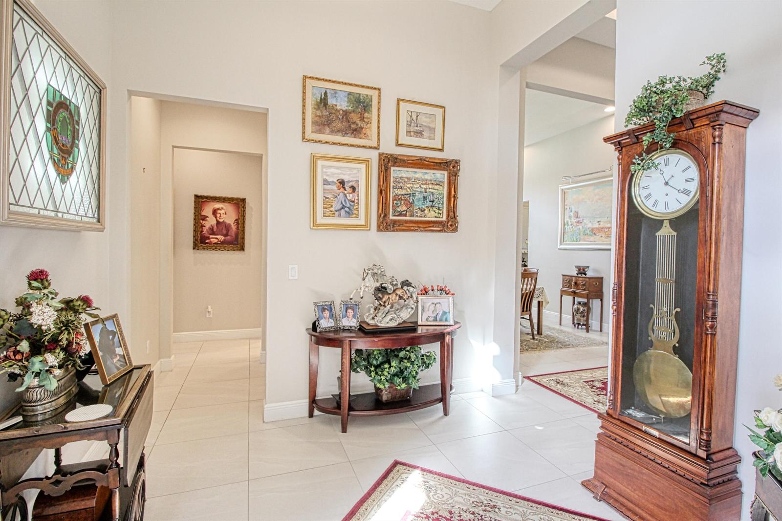 A bright foyer features tile flooring, a grandfather clock, a console table, and framed artwork — 12095 Bastille Circle E, Parkland FL 33076, PARKLAND, FL