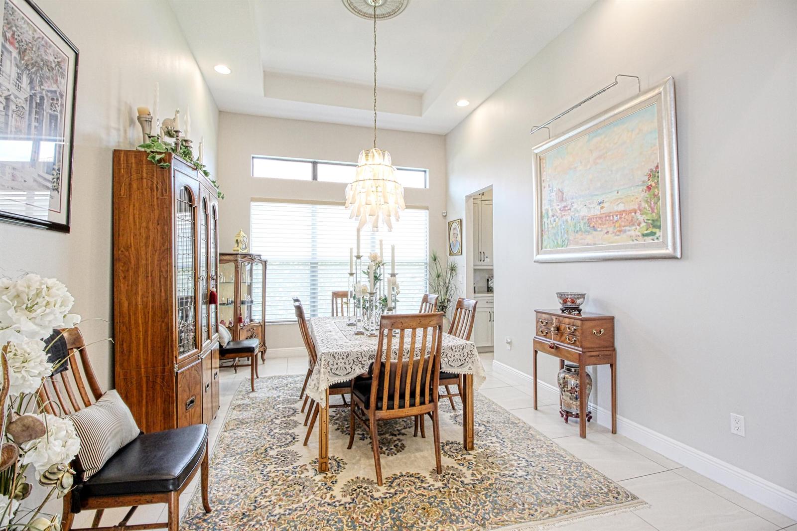 A formal dining room features a wooden table, chairs, a chandelier, and a patterned rug — 12095 Bastille Circle E, Parkland FL 33076, PARKLAND, FL