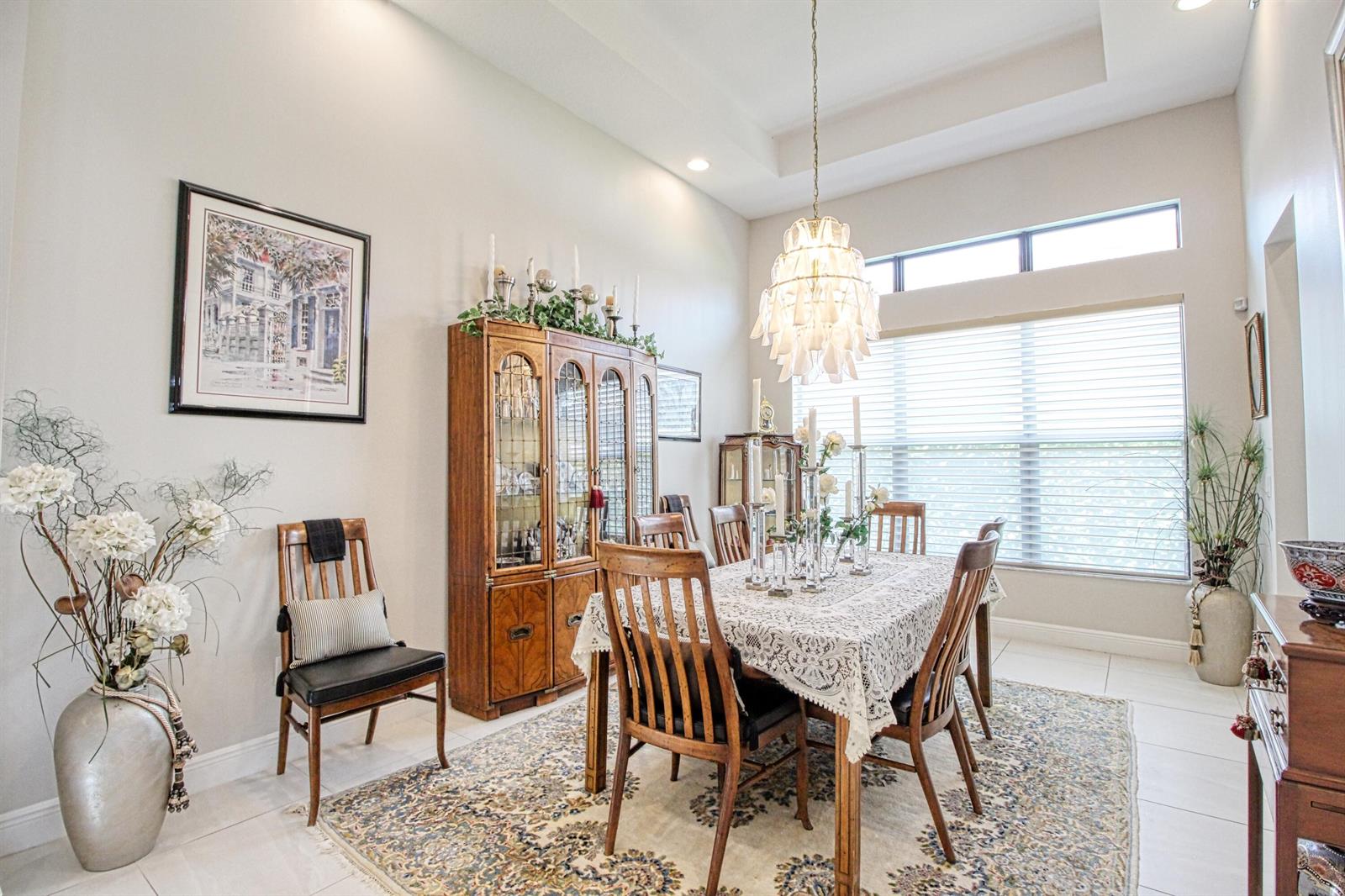 A formal dining room features a wooden table, chairs, a hutch, and a chandelier — 12095 Bastille Circle E, Parkland FL 33076, PARKLAND, FL