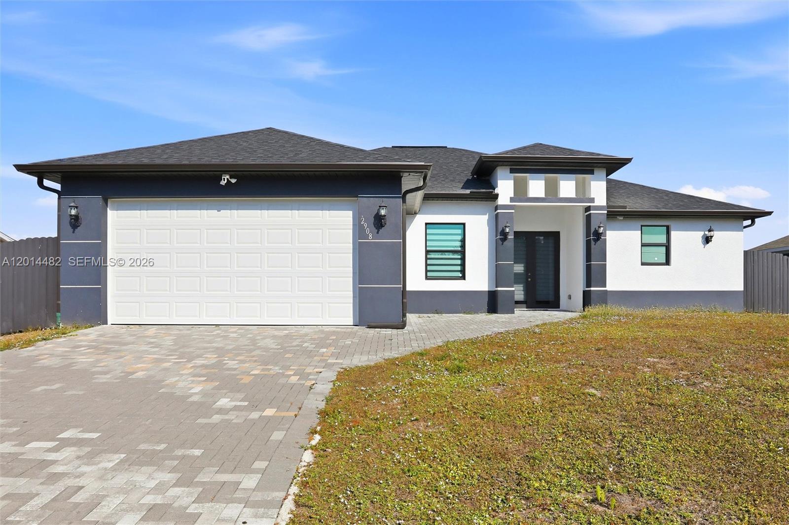 A modern single-story house with a two-car garage, white stucco walls, and dark trim — 2908 SW 9th ST, Lehigh Acres FL 33976, LEHIGH ACRES, FL