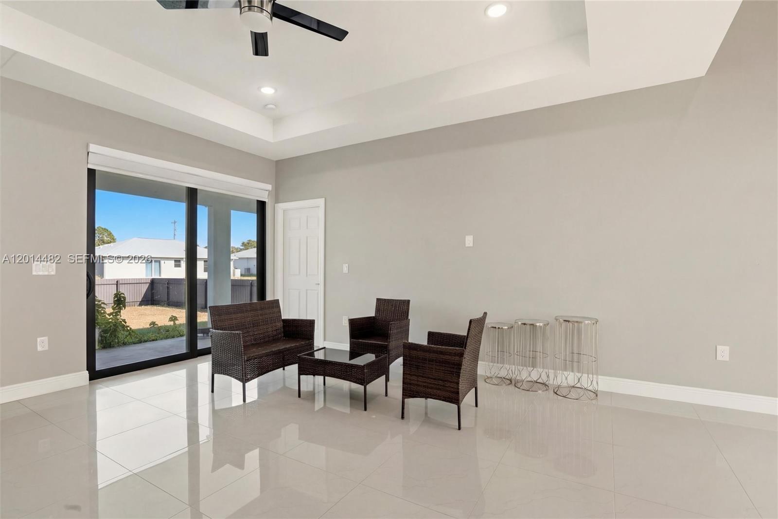 A living room with a tray ceiling, tile floors, and a sliding glass door — 2908 SW 9th ST, Lehigh Acres FL 33976, LEHIGH ACRES, FL