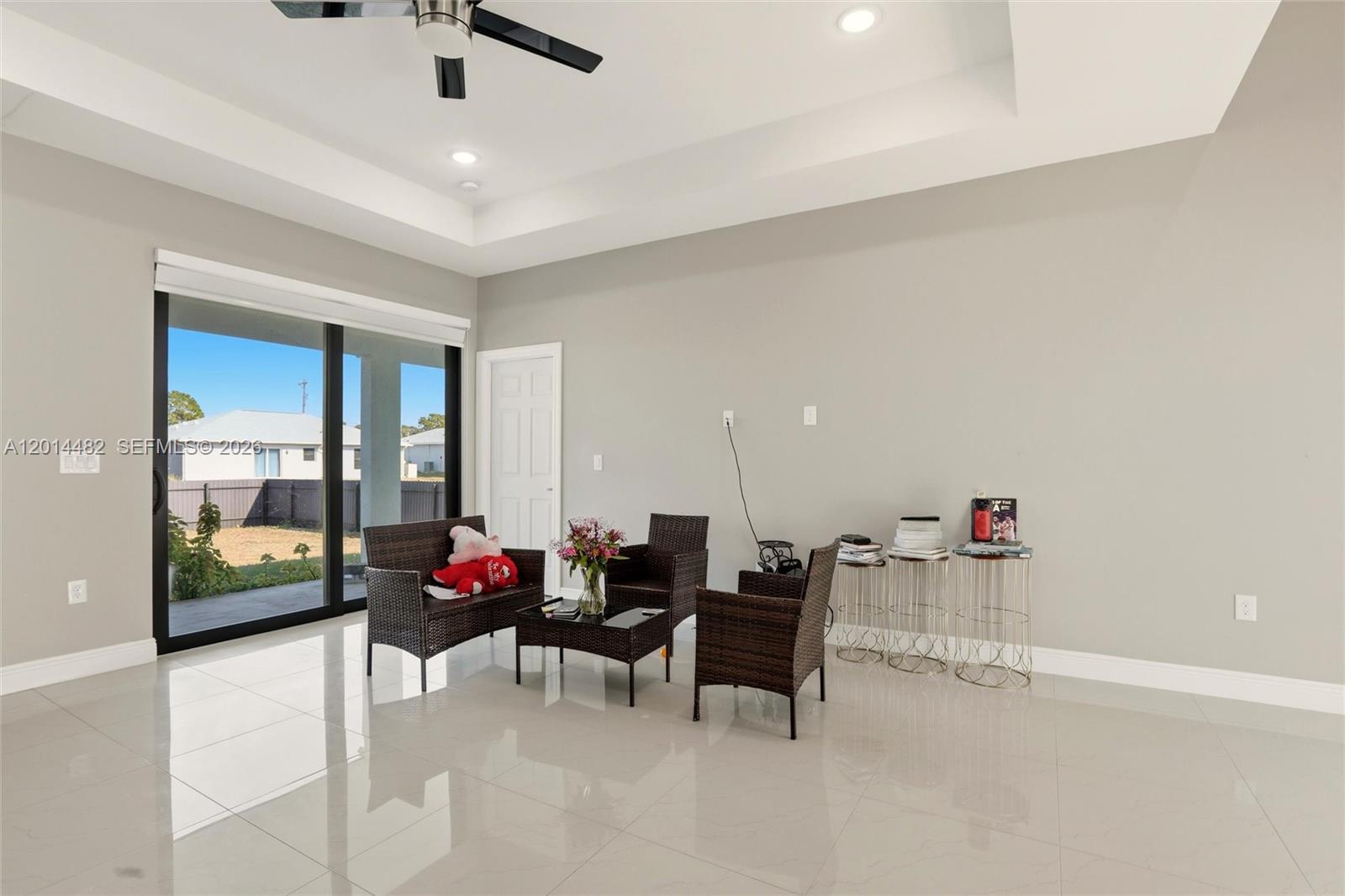 A living room features light gray walls, white tile flooring, a tray ceiling, and sliding doors — 2908 SW 9th ST, Lehigh Acres FL 33976, LEHIGH ACRES, FL