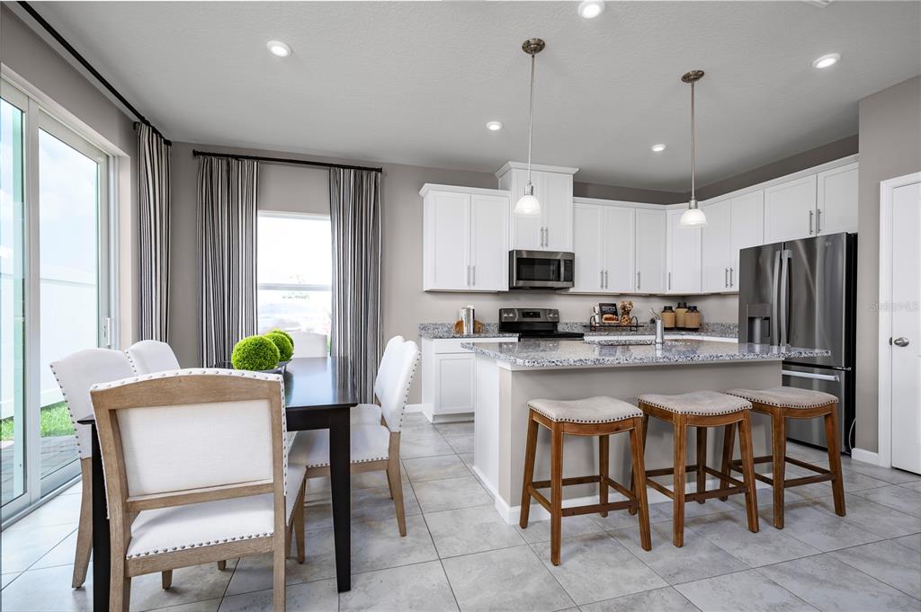 A kitchen and dining area with white cabinets, granite countertops, and a center island — 2604 LANDING DRIVE, TITUSVILLE, FL
