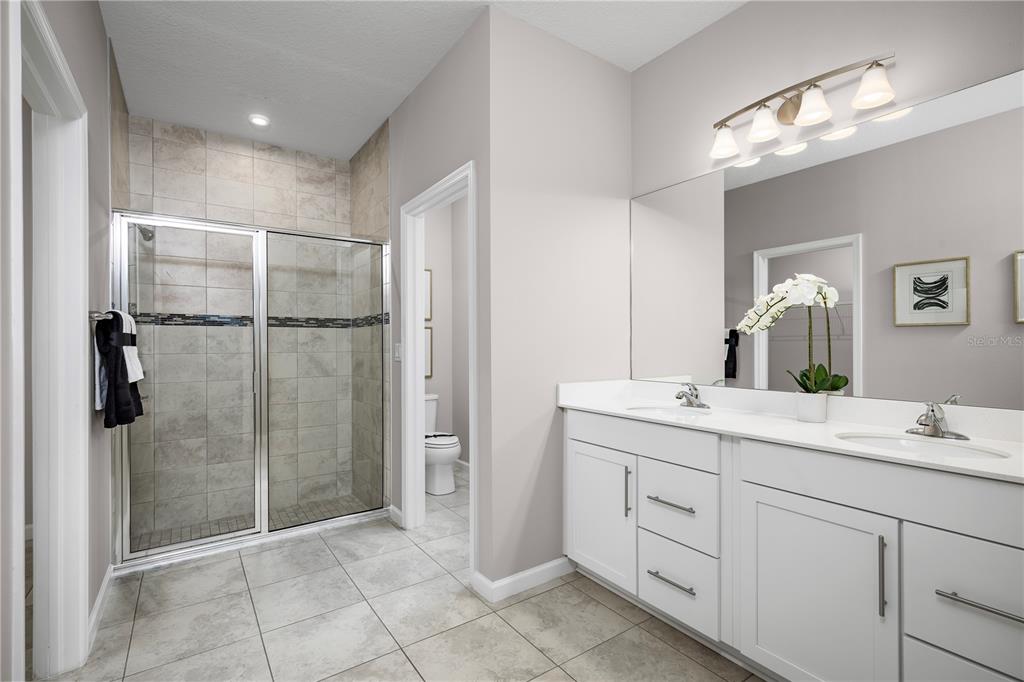 A bathroom with a tiled walk-in shower, double vanity, and a separate toilet room — 2604 LANDING DRIVE, TITUSVILLE, FL