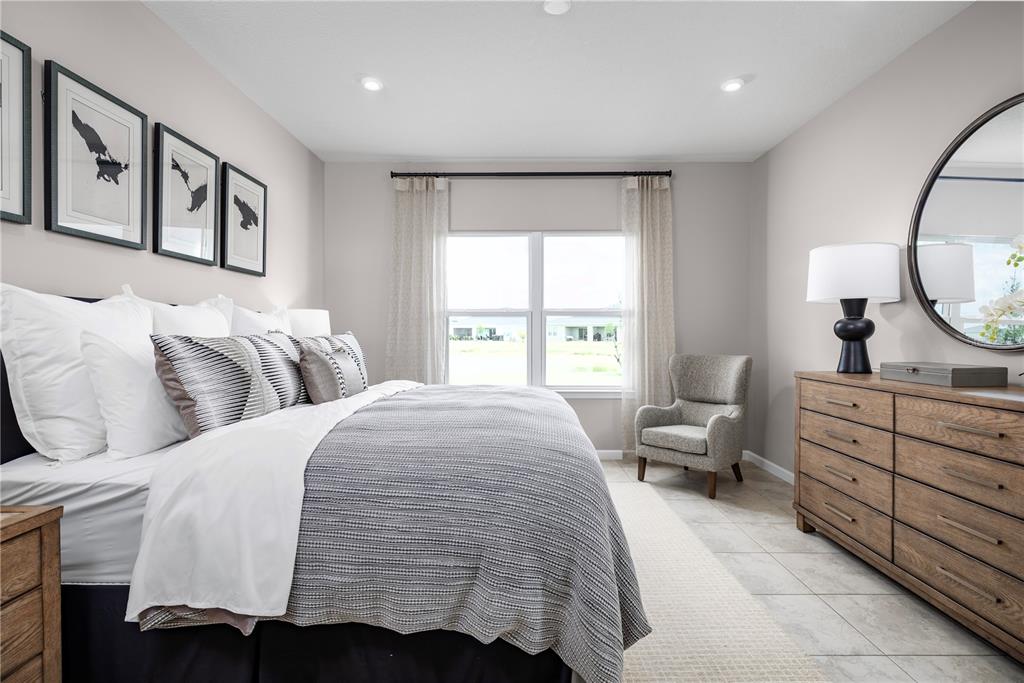 A bedroom features a bed with a gray quilt, a dresser, and a corner chair — 2604 LANDING DRIVE, TITUSVILLE, FL