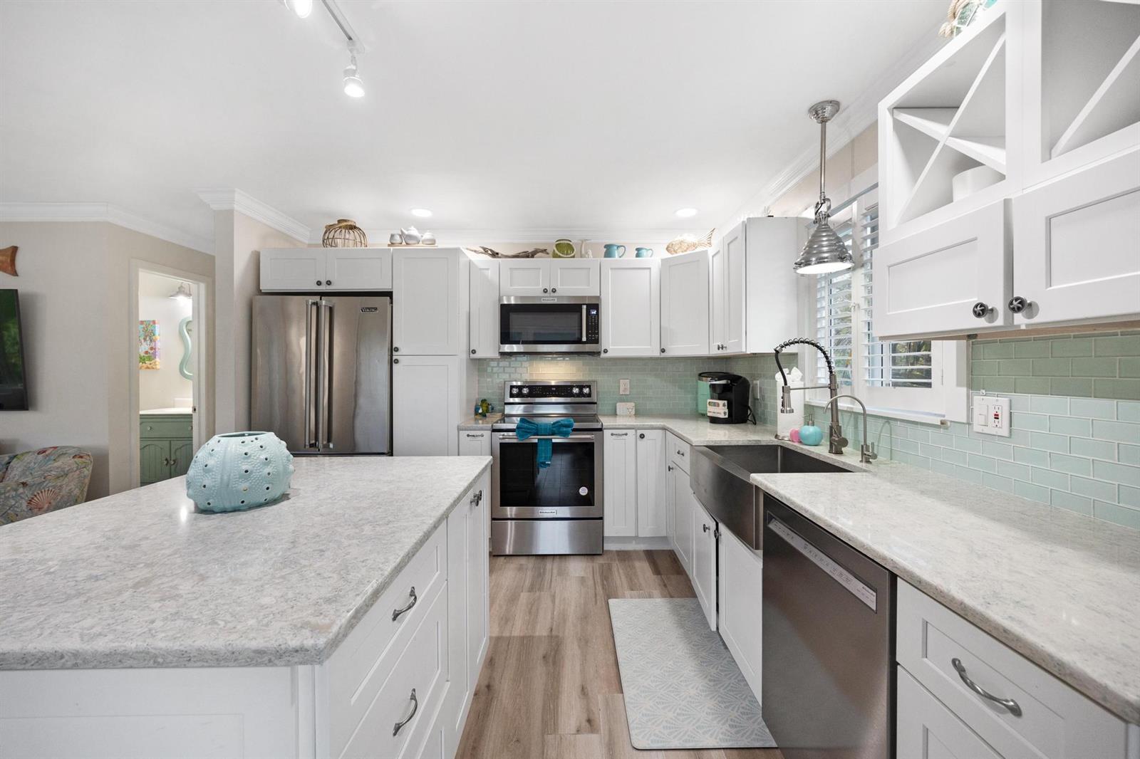A kitchen with white cabinets, stainless steel appliances, an island, and light green backsplash tiles — 116 Spanish Main Drive, FL 33042, FL