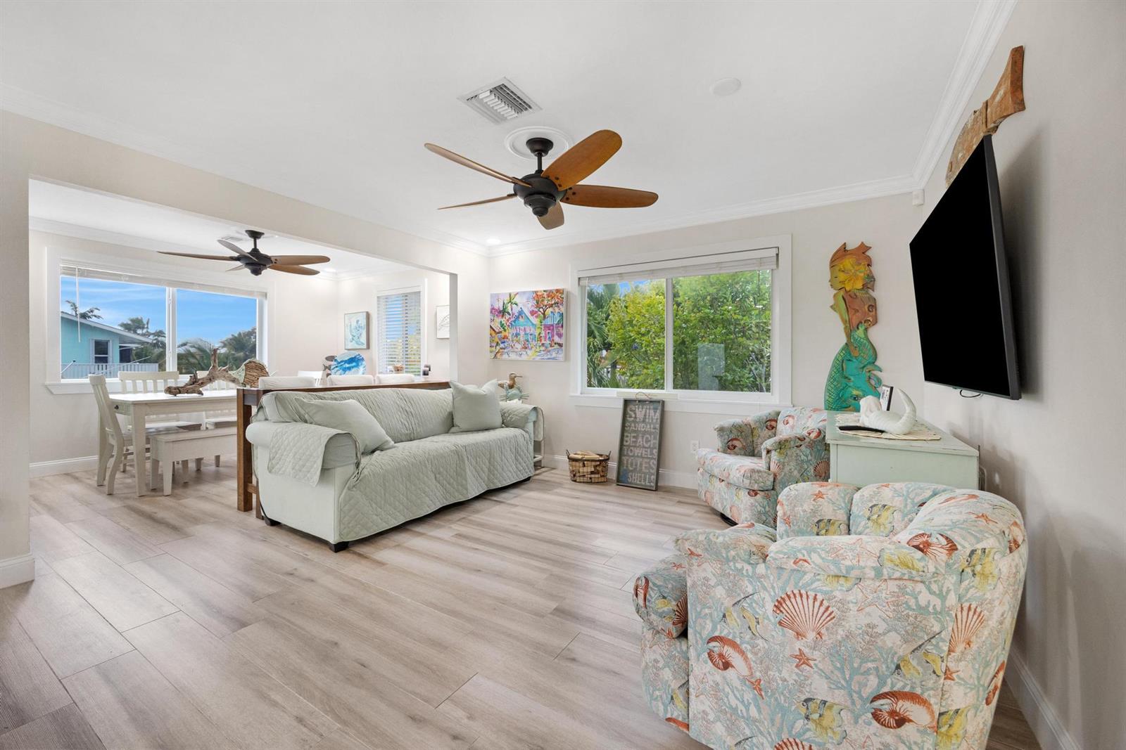 A living room with light wood floors, a sofa, two patterned armchairs, and a television — 116 Spanish Main Drive, FL 33042, FL
