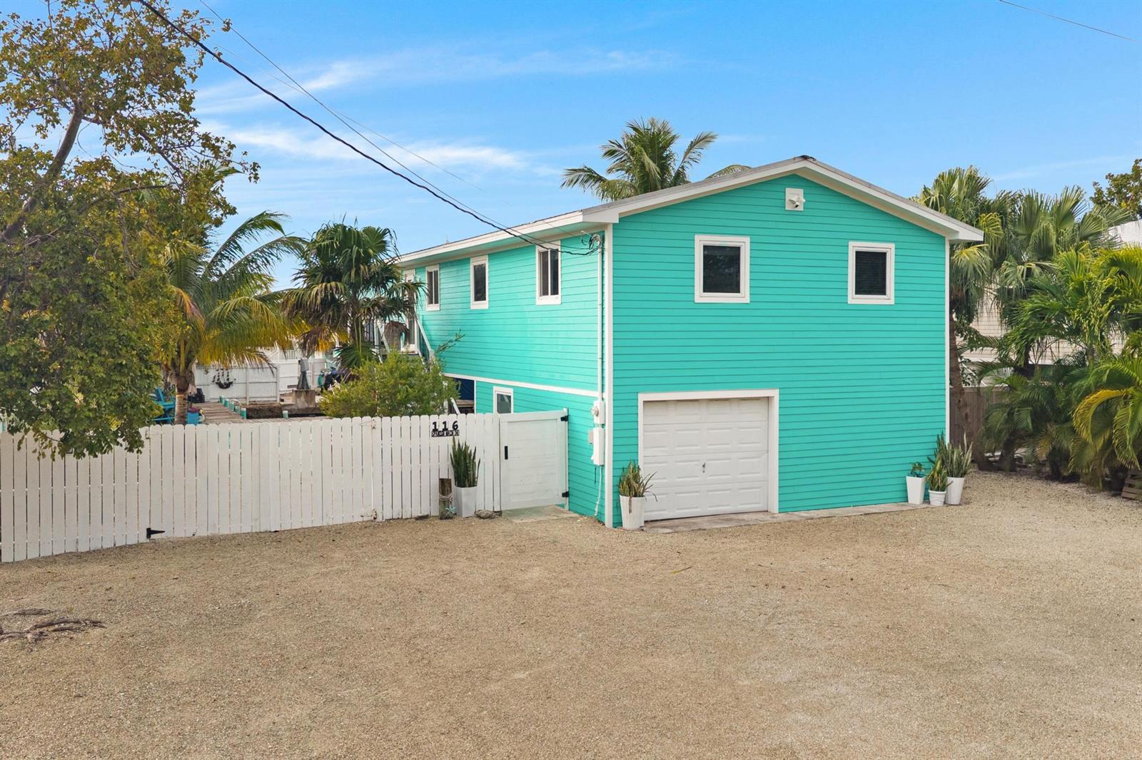 A two-story teal house with a white garage door and a white picket fence — 116 Spanish Main Drive, FL 33042, FL