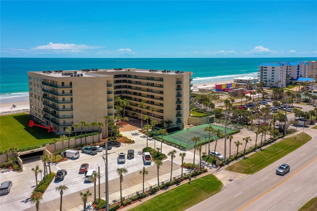 An aerial view shows a multi-story beachfront condominium building with a tennis court and parking — 4575 S ATLANTIC AVENUE UNIT 6101, PORT ORANGE, FL