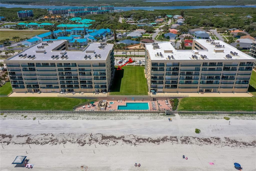 An aerial view shows two beachfront condominium buildings separated by a grassy courtyard and pool — 4575 S ATLANTIC AVENUE UNIT 6101, PORT ORANGE, FL