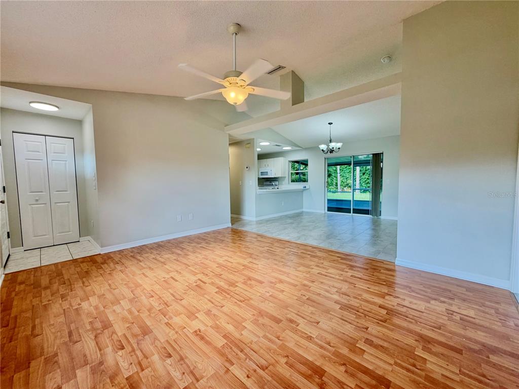 A living room with wood-look flooring leads to a tiled kitchen and dining area — 30 RIDLEY LANE, PALM COAST, FL