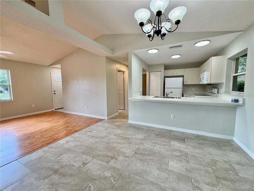 An open-concept living area features wood-look flooring, a tiled kitchen, and a breakfast bar — 30 RIDLEY LANE, PALM COAST, FL