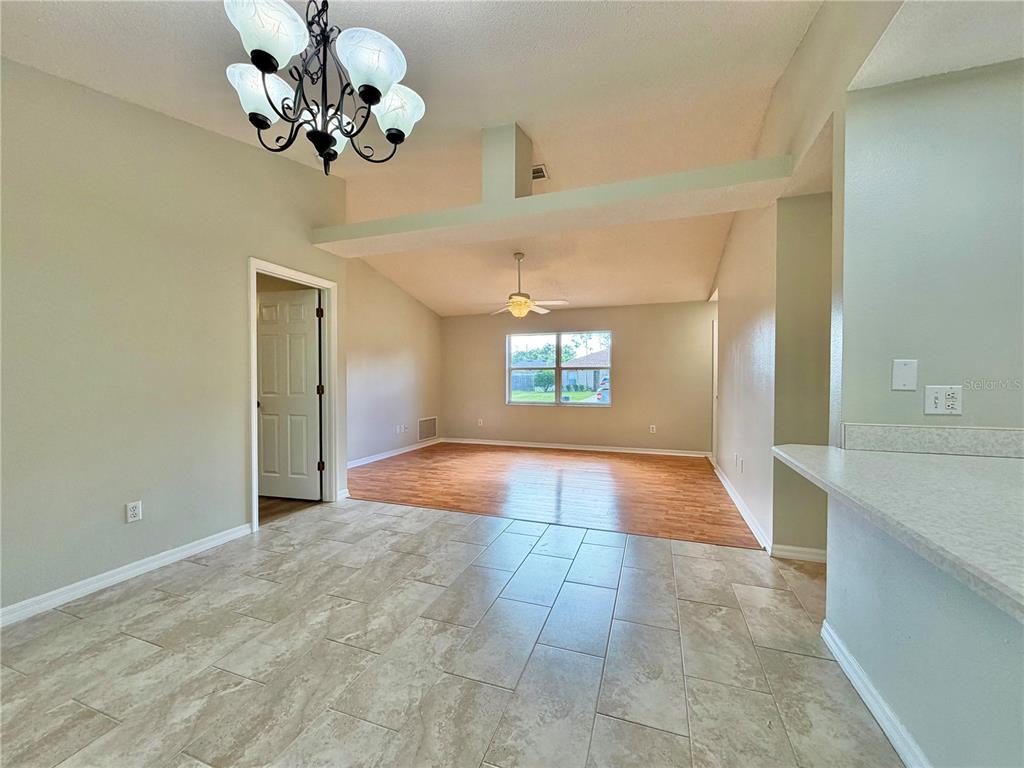 An interior view shows a dining area with tile flooring transitioning to a wood-floored living room — 30 RIDLEY LANE, PALM COAST, FL