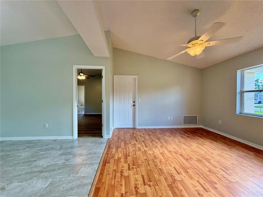 A room with wood-look flooring, a vaulted ceiling, a ceiling fan, and a doorway — 30 RIDLEY LANE, PALM COAST, FL