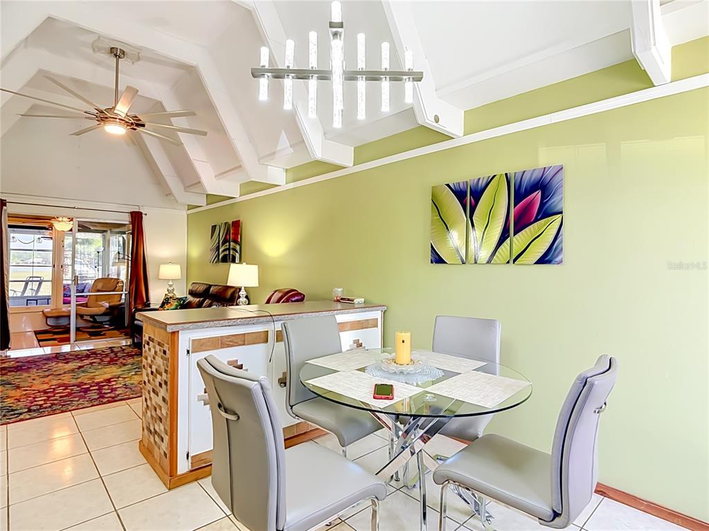 A room with a vaulted ceiling, light green wall, tile flooring, and a modern chandelier — 523 CLUB CIRCLE, LAKE WALES, FL