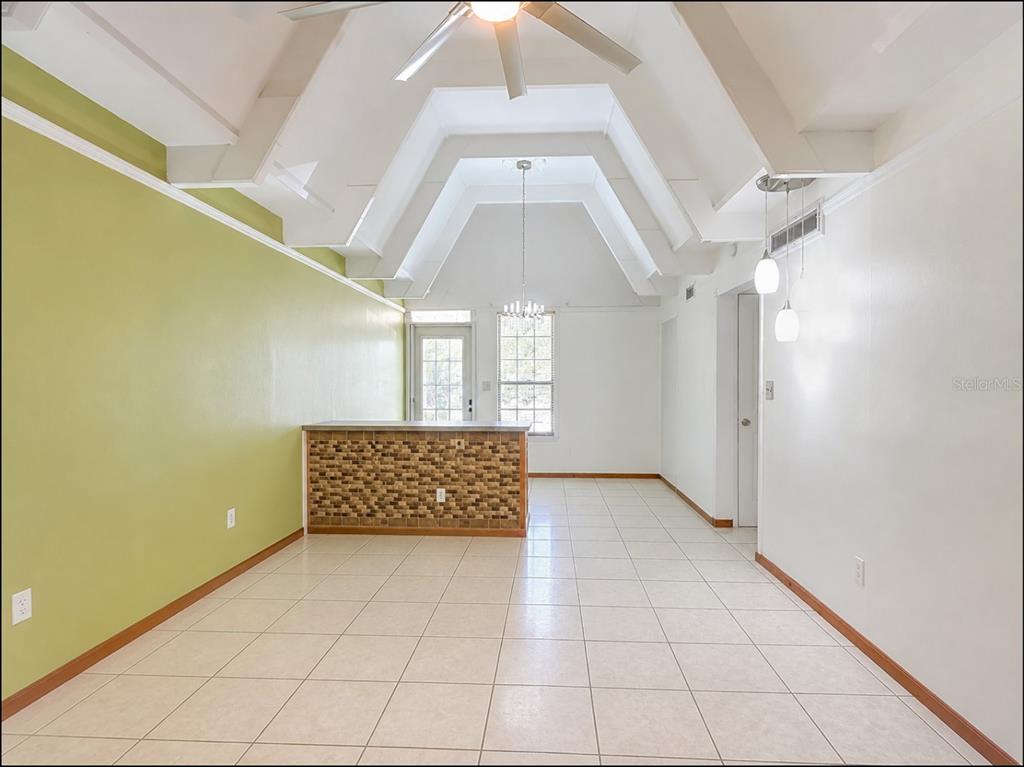 A dining area with a glass table, gray chairs, and a vaulted ceiling with beams — 523 CLUB CIRCLE, LAKE WALES, FL