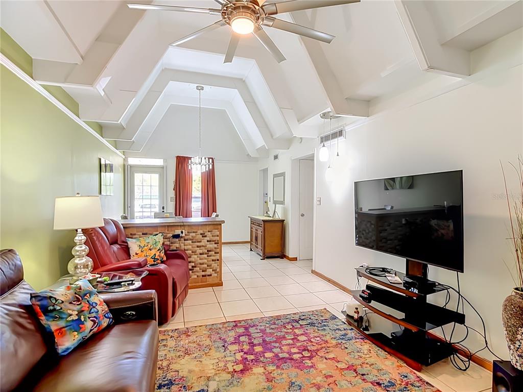 A room with a vaulted ceiling, tiled floor, green accent wall, and a tiled breakfast bar — 523 CLUB CIRCLE, LAKE WALES, FL