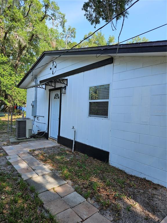 A white concrete block house exterior with a paved walkway and an outdoor air conditioning unit — 345 N THOMPSON ROAD UNIT B, APOPKA, FL