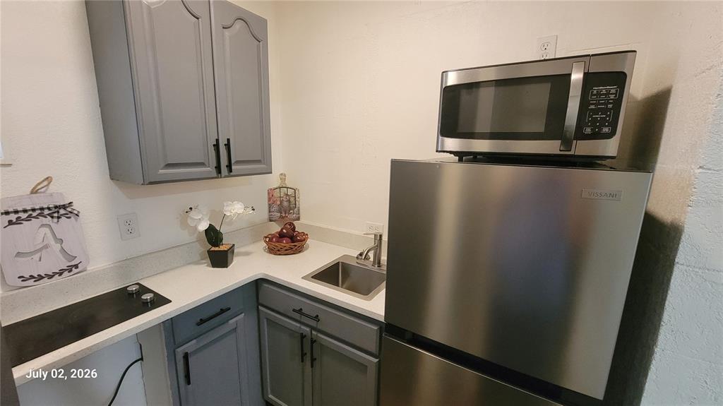 A small kitchen features gray cabinets, a stainless steel refrigerator, a microwave, and a sink — 345 N THOMPSON ROAD UNIT B, APOPKA, FL