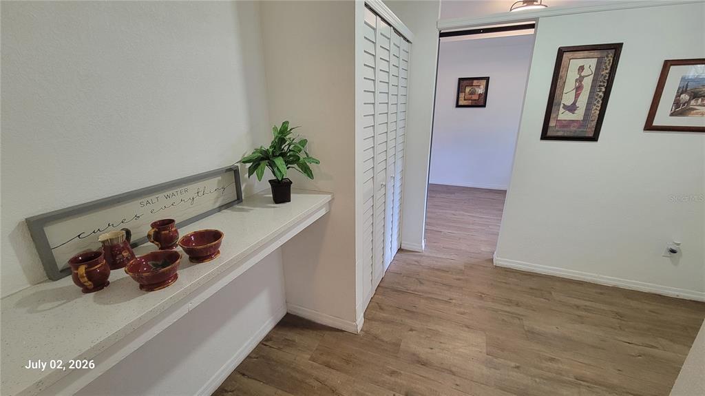 A hallway features wood-look flooring, a built-in counter with decor, and a white louvered closet — 345 N THOMPSON ROAD UNIT B, APOPKA, FL