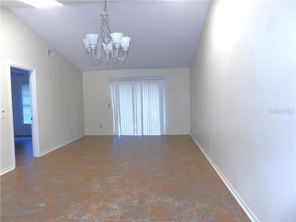 An empty dining area features tile flooring, a chandelier, and sliding glass doors — 1809 COLONADE STREET, INVERNESS, FL