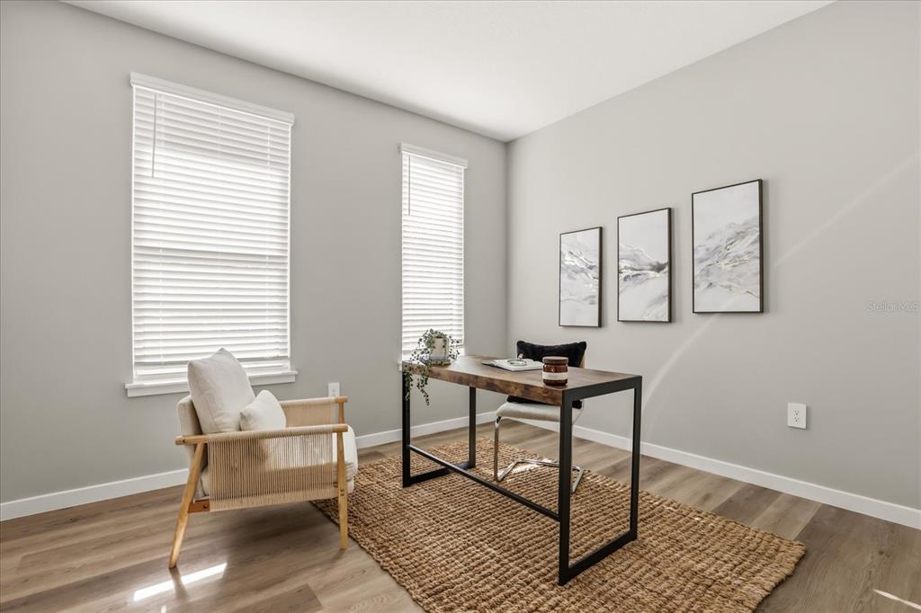 A home office features a wooden desk, an armchair, and three wall-mounted abstract art pieces — 2316 E CONCORD STREET UNIT 9, ORLANDO, FL