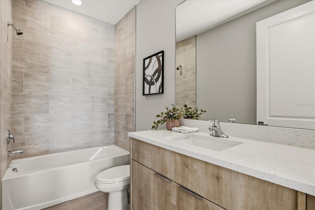 A bathroom features a light wood vanity, white countertop, and a tub with tiled walls — 2316 E CONCORD STREET UNIT 9, ORLANDO, FL