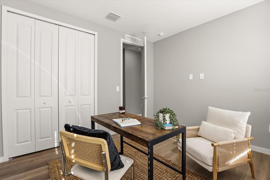 A home office features a wooden desk, two chairs, a closet, and light gray walls — 2316 E CONCORD STREET UNIT 9, ORLANDO, FL