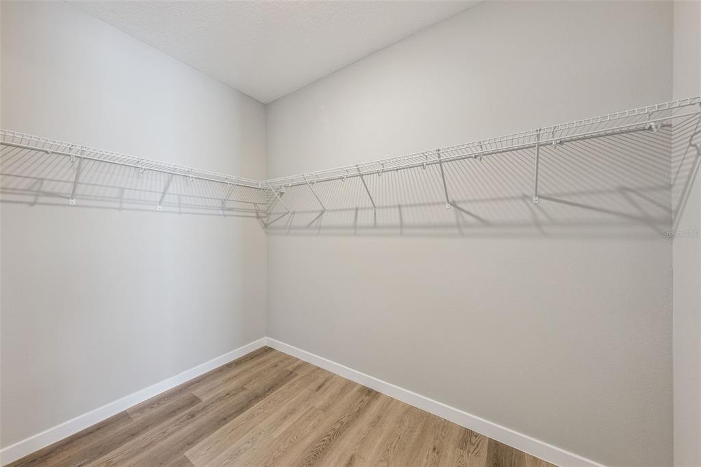 A walk-in closet features light gray walls, wood-look flooring, and white wire shelving — 2316 E CONCORD STREET UNIT 9, ORLANDO, FL