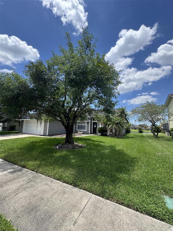 A single-story house with a large front tree, a white garage, and a green lawn — 14760 EAGLES CROSSING DRIVE, ORLANDO, FL