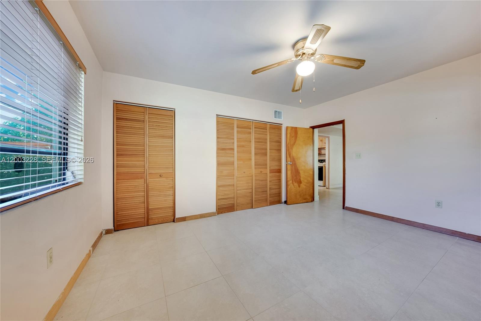 A bedroom features light tile flooring, louvered wood closet doors, and a ceiling fan — 14115 NW 6th Ave, North Miami FL 33168, NORTH MIAMI, FL
