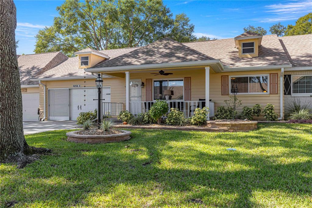 A single-story house with yellow siding, a covered front porch, and a landscaped front yard — 9256 SW 82ND TERRACE UNIT E, OCALA, FL